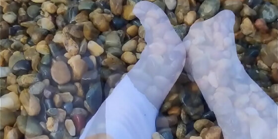 playing with my feet in white socks with pebbles on the beach
